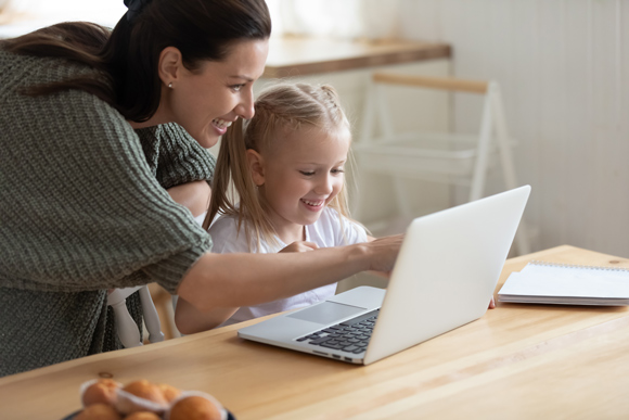 parent helping child on laptop smiling