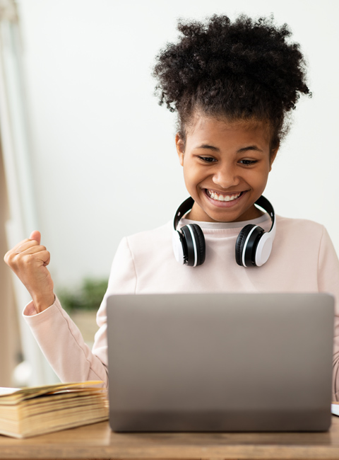 smiling happy young girl on laptop with headphones around neck